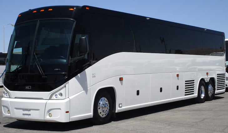 a plain white MCI charter bus parked on pavement